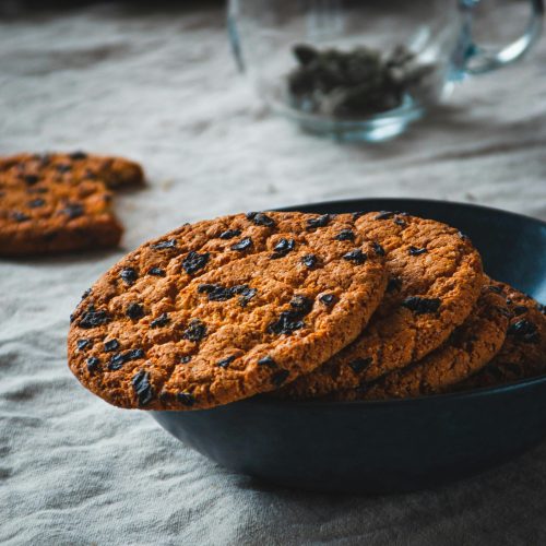 Warm and rustic close-up of chocolate chip cookies in a black bowl, perfect for dessert themes.