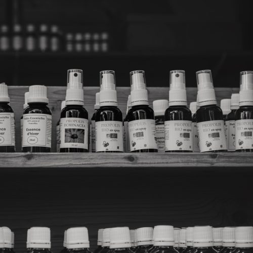 A black and white image of natural health products on wooden shelves at a market.