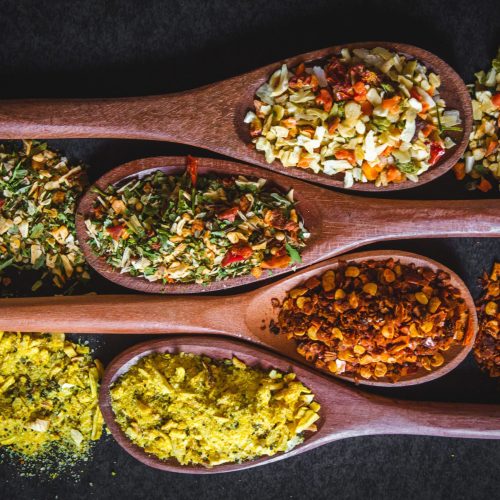Vibrant spices and herbs displayed in wooden spoons, perfect for culinary inspiration.