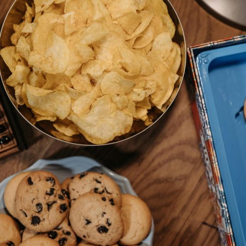 Vibrant snack assortment with chips and cookies on a wooden table.