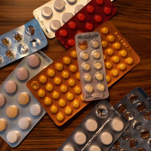 Colorful blister packs of medicine pills on a wooden surface, viewed from above.